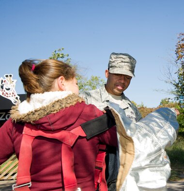 Staff Sgt. Alfred Mines, 22nd Civil Engineer Squadron firefighter, helps a child try on firefighters’ protective equipment to help promote fire safety week Oct. 9, 2012, Wichita, Kan. Several McConnell firefighters supported fire prevention week by demonstrating their equipment and personnel at the Sedgwick County Zoo. (U.S. Air Force photo/ Senior Airman Armando A. Schwier-Morales)
