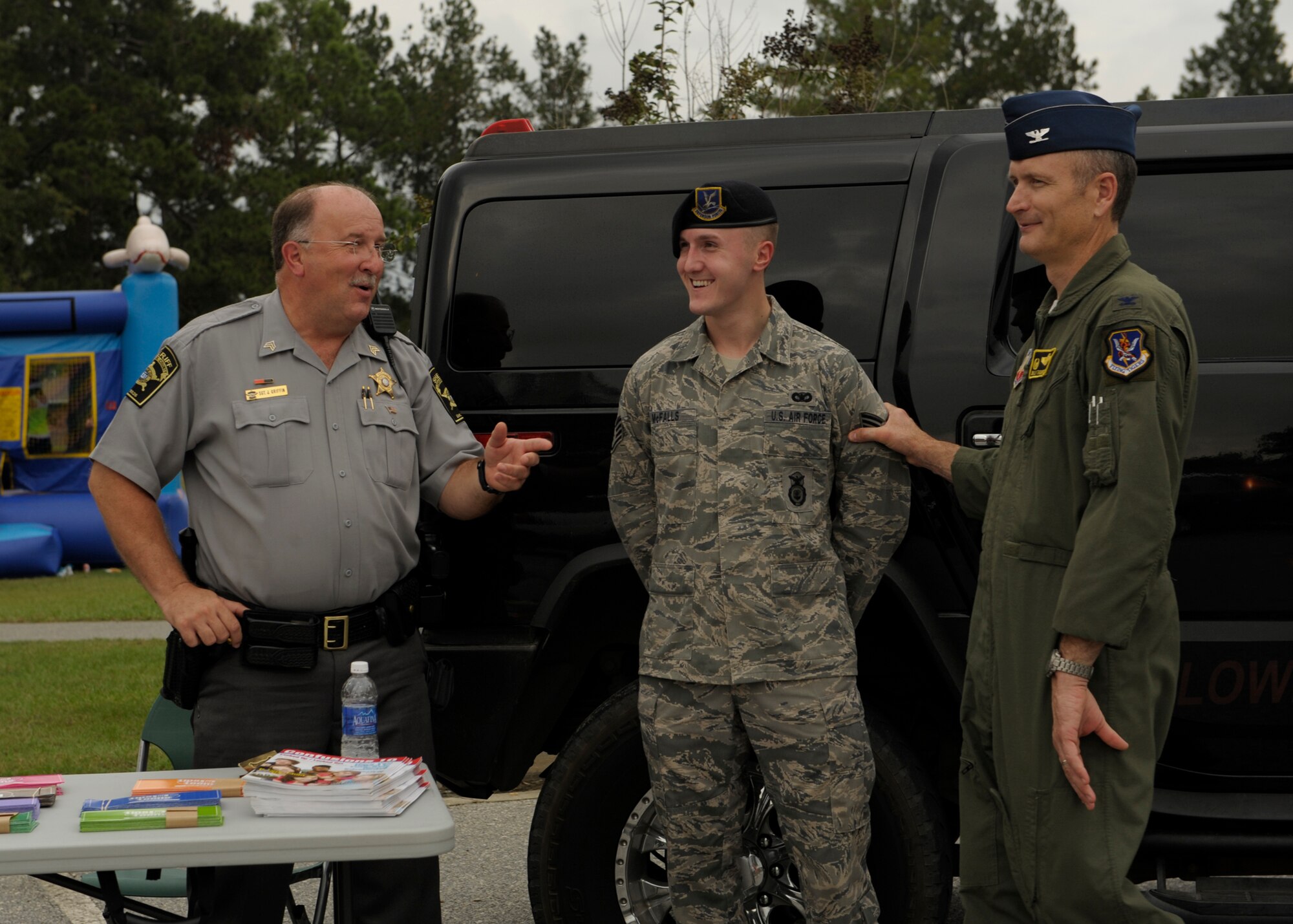 A member of the Lowndes County Sheriff’s Department passes out pamphlets on neighborhood safety while speaking with U.S. Air Force Staff Sgt. Joshua McFalls, 23d Security Forces Squadron, and Col. Billy Thompson, 23d Wing commander, during the National Night Out Oct. 4, 2012, at Moody Air Force Base, Ga. There was food, a DJ, bouncy castle, and lots of information to support the event which encourages kids of the Moody family housing units to be aware of crime. (U.S. Air Force photo by Senior Airman Eileen Meier/Released)