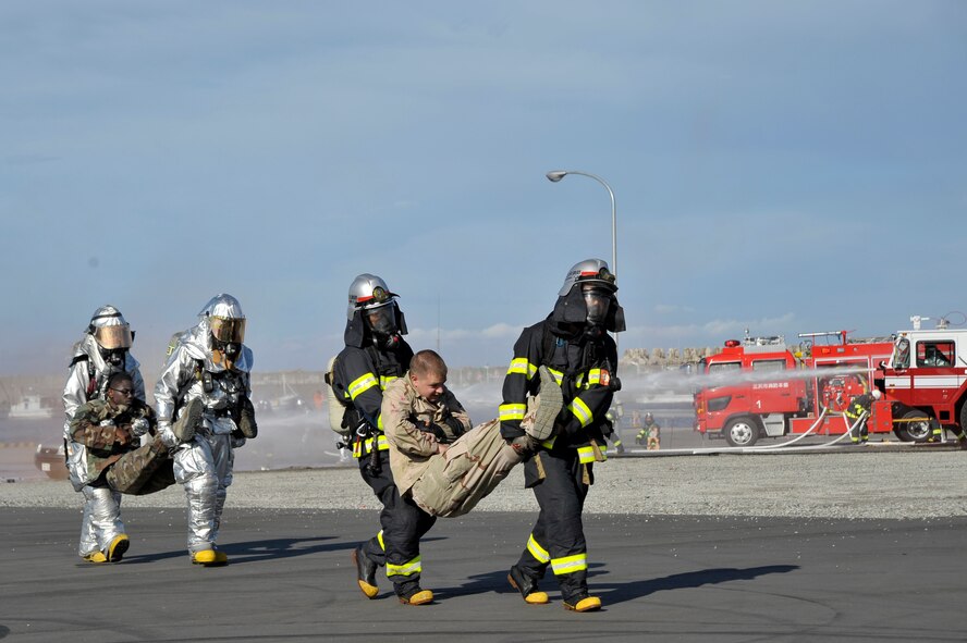 U.S. Air Force firefighters from the 35th Civil Engineer Squadron, left, and Misawa City firefighters carry simulated casualties during an Emergency Management Exercise at the Misawa City Port, Misawa, Japan, Oct. 5, 2012. The purpose of the EME was to prepare for unexpected emergencies and strengthen the already strong bilateral relationship. (U.S. Air Force photo by Staff Sgt. Nathan Lipscomb)