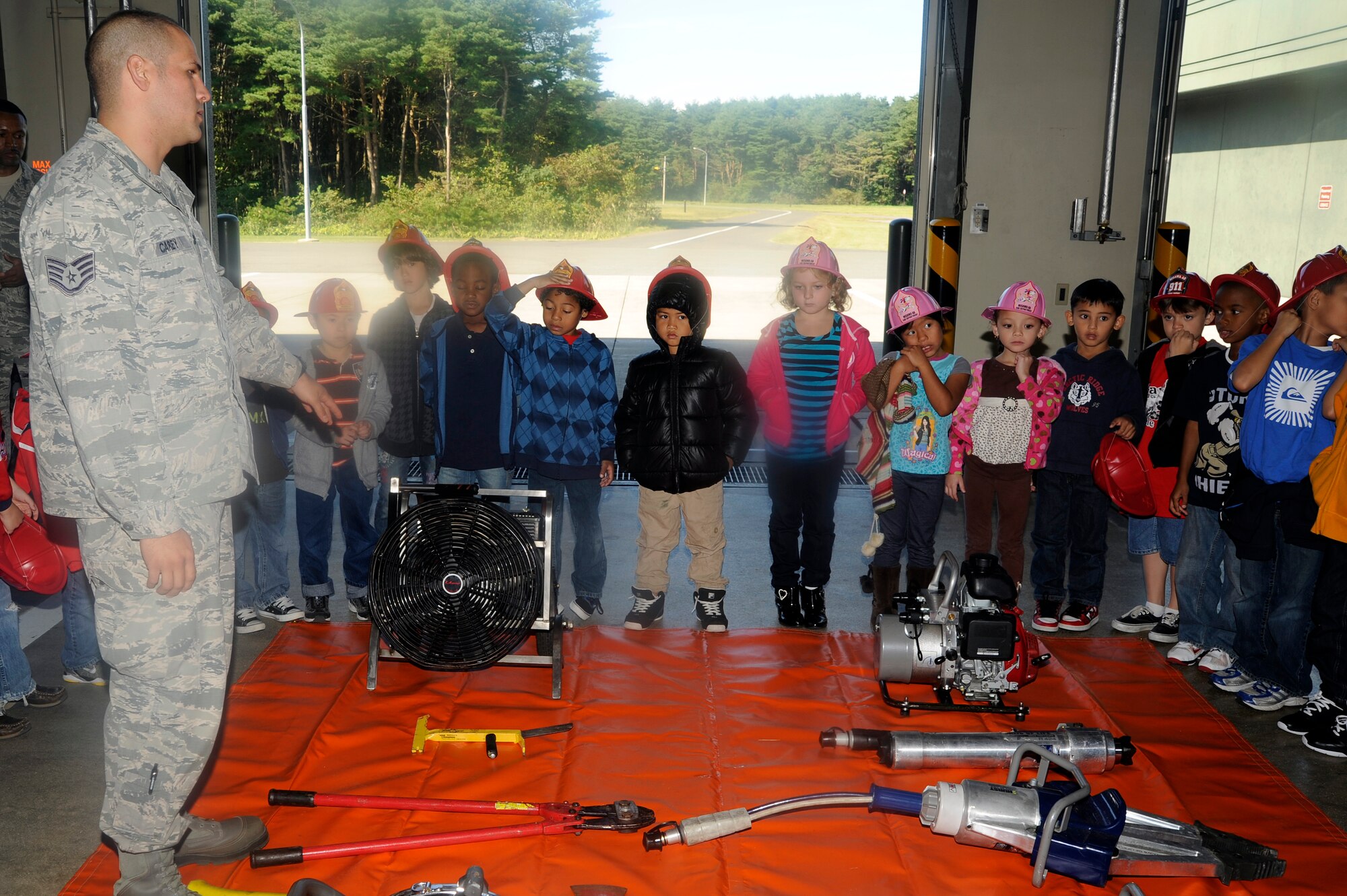 U.S. Air Force Staff Sgt. Christopher Carey, 35th Civil Engineer Squadron firefighter, shows first grade students from Sollars Elementary School tools that are used by firefighters at Misawa Air Base, Japan, Oct. 9, 2012. This year's theme for fire prevention week is "Have two ways out", which emphasizes readiness in the event of a fire or other emergency. (U.S. Air Force photo by Tech. Sgt. Marie Brown)