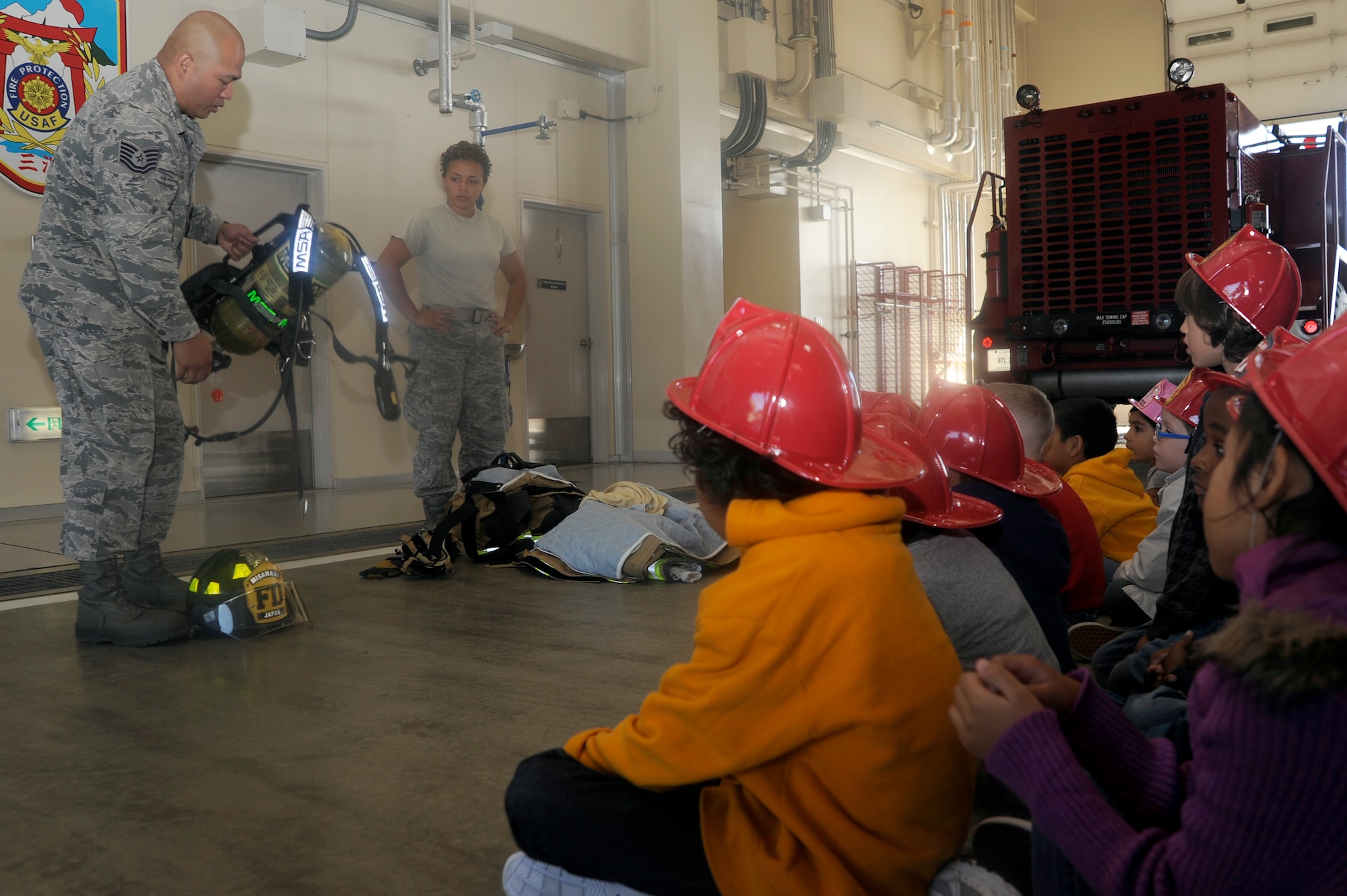 U.S. Air Force Tech. Sgt. Philip Narcis, left, 35th Civil Engineer Squadron firefighter, and Airman 1st Class Hillary Rodriguez, 35 CES firefighter, talk to first grade students from Sollars Elementary School about gear that firefighters wear during fire prevention week at Misawa Air Base, Japan, Oct. 10, 2012. Fire prevention week is dedicated to providing the community with sound fire prevention, safety knowledge and promotion of a fire-safe lifestyle. (U.S. Air Force photo by Tech. Sgt. Marie Brown)
