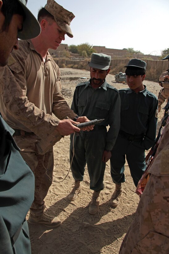 U.S. Marine Corps Sgt. Benjamin T. Fischer, left, shows an example of a pressure plate used to detonate an improvised explosive device to Afghan police trainees on Forward Operating Base Musa Qa'leh in Afghanistan's Helmand province, Oct. 4, 2012. Fischer, an explosives ordnance disposal specialist, is assigned to Combat Logistics Regiment 15, Regimental Combat Team 6.