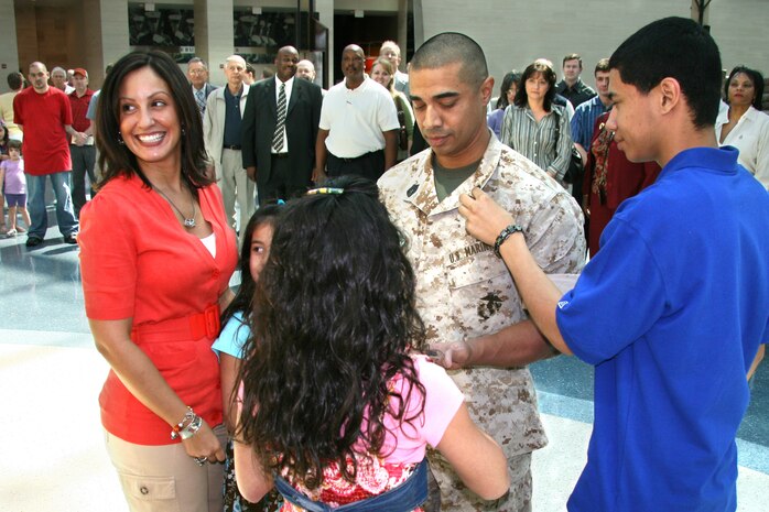 Family members assist Reserve Master Sergeant Angel Huertas with his new collar devices during his 2010 promotion ceremony. As a civilian, Huertas is a Security Cooperation Specialist with International Programs. 