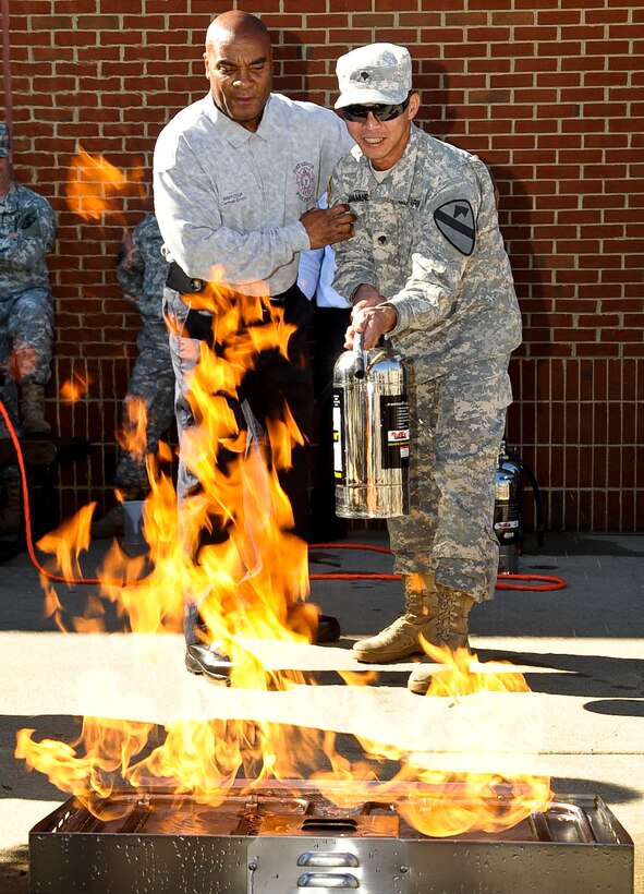 U.S. Army Spc. Jefrey Jamandre (right), assigned to the 1-222nd Aviation Regiment Hotel Company, receives instruction from Carneal Smith, a Fort Eustis Fire Department inspector, during a fire extinguisher exhibition at the Exchange at Fort Eustis, Va., Oct. 11, 2012. The exhibition was part of the department's Fire Prevention Week activities, designed to raise awareness about fire prevention and safety in the post community. (U.S. Air Force photo by Staff Sgt. Wesley Farnsworth/Released)