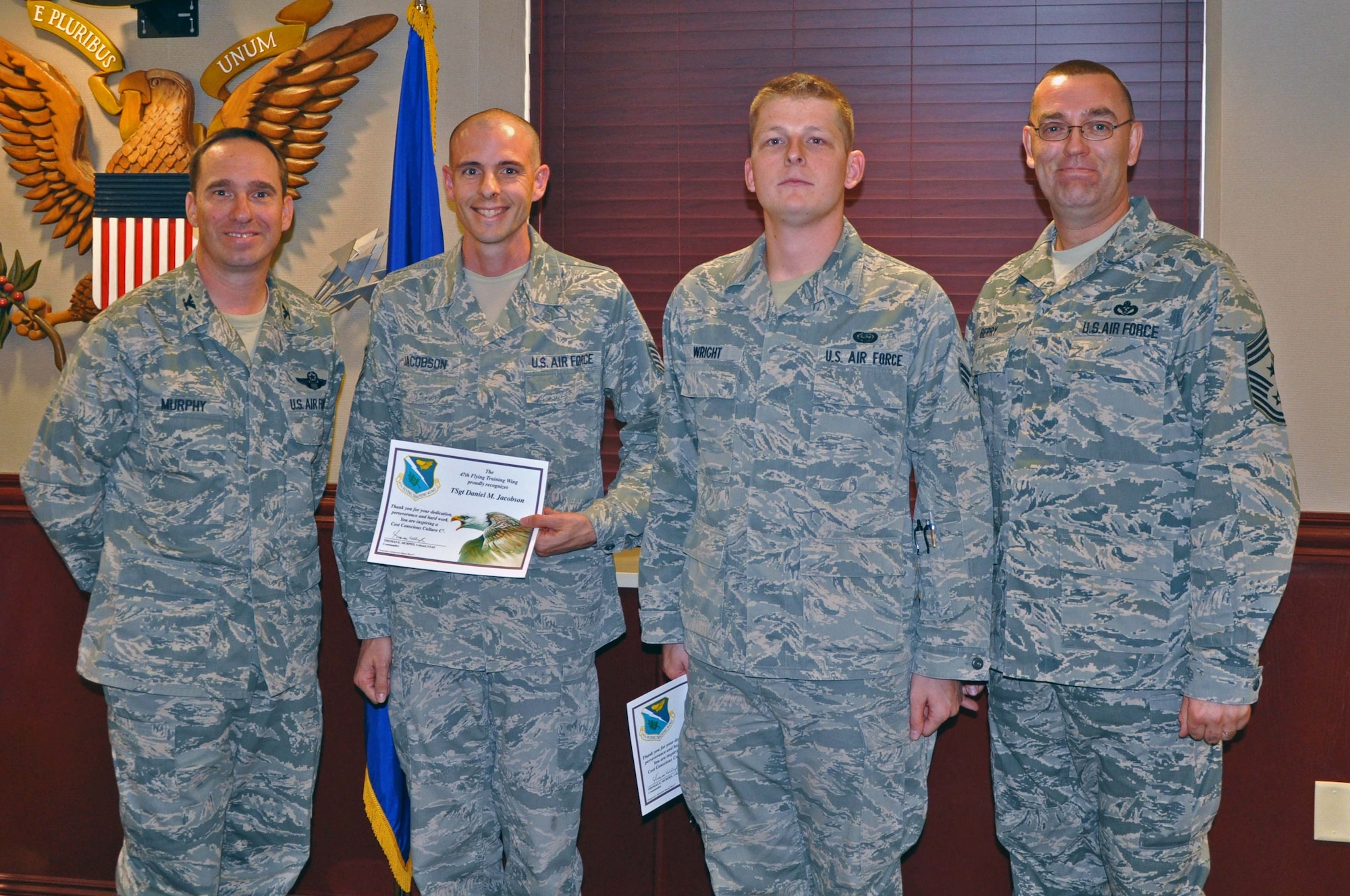 Tech. Sgt. Daniel Jacobson and Senior Airman Brenden Wright, both from the 47th Communications Squadron, pose with Col. Tom Murphy, 47th Flying Training Wing commander, and Chief Master Sgt. Garry Berry, 47th FTW command chief, after receiving the Cost Conscious Culture Award at Laughlin Air Force Base, Texas, Oct. 2, 2012. The two Airmen were recognized for promoting an idea that conserved an estimated $30,000 (U.S. Air Force photo/Joel Langton)