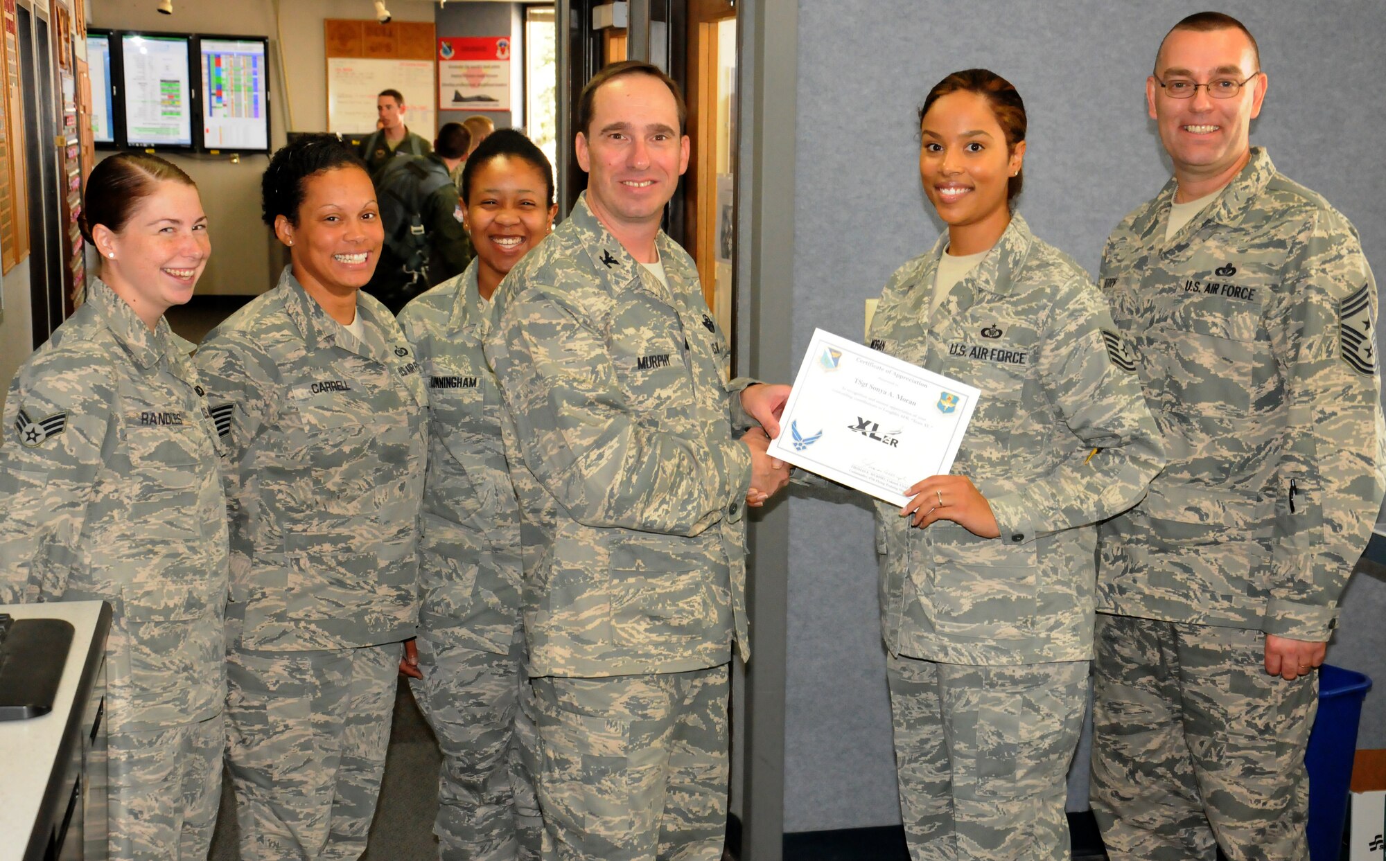 Tech Sgt. Sonya Moran, 85th Flying Training Squadron NCO in charge aviation resource manager, poses with Col. Tom Murphy, 47th Flying Training Wing commander, and Chief Master Sgt. Garry Berry, 47th FTW command chief, after being presented the XLer of the week award at Laughlin Air Force Base, Texas, Sept. 18, 2012. The XLer is a weekly award chosen by wing leadership and given to those who consistently make outstanding contributions to Laughlin and their unit. (U.S. Air Force photo/2nd Lt. Daniel Brand)
