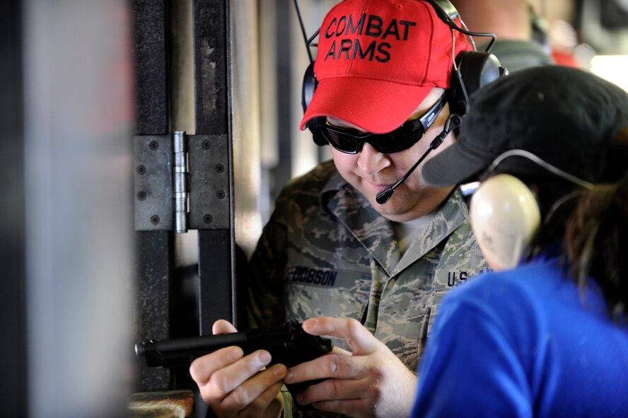 MINOT AIR FORCE BASE, N.D. -- Air National Guardsman Master Sgt. Charlie Dobson, 219th Security Forces Squadron combat arms training and maintenance instructor, briefs a key spouse here on the proper use of a pistol, Oct. 6. Team Minot Key Spouses had the opportunity to take part in this shooting event to get a feeling for what some of the training security forces members take part in. (U.S. Air Force photo/Senior Airman Jesse Lopez)


