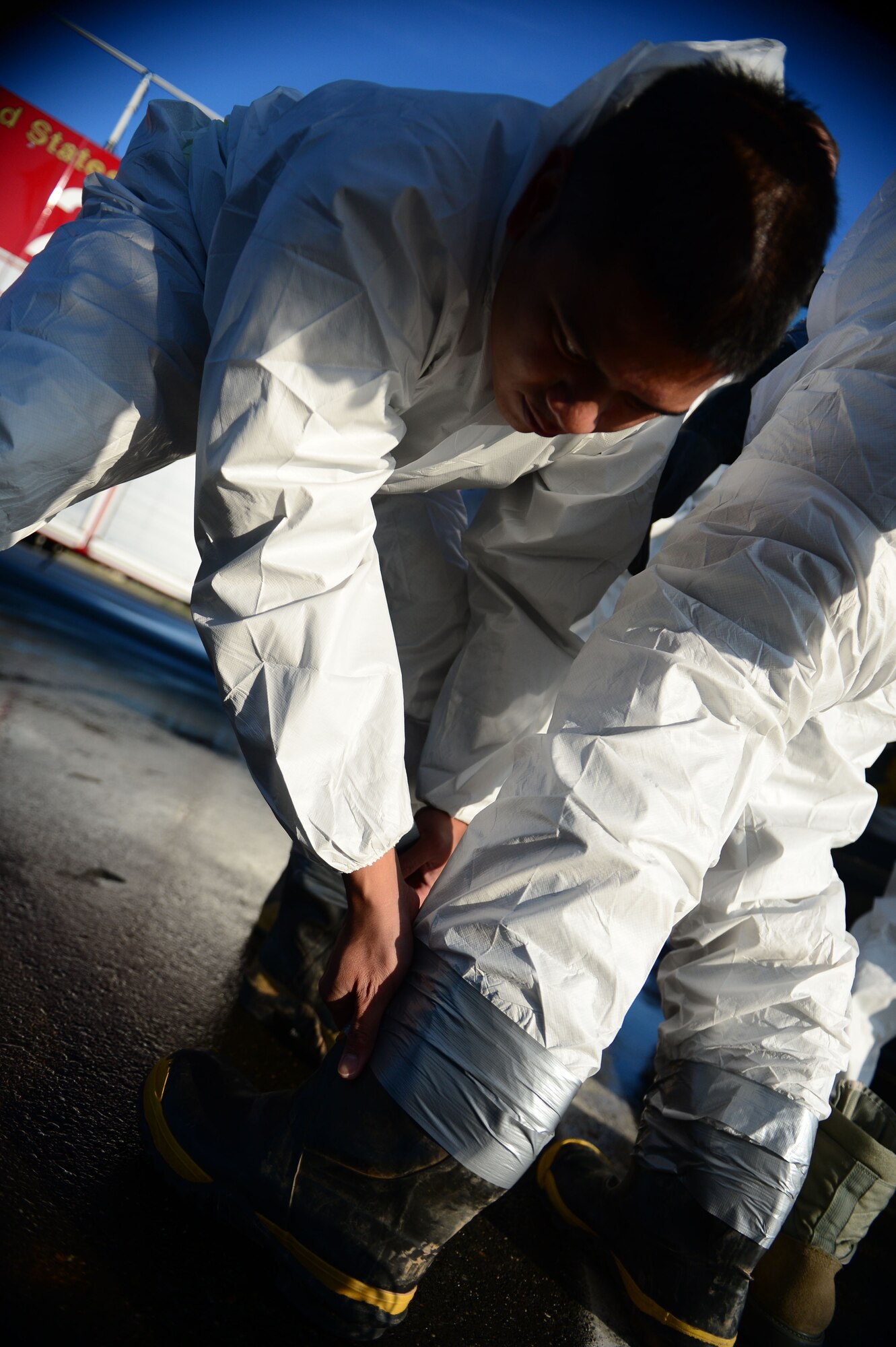 SPANGDAHLEM AIR BASE, Germany – U.S. Air Force Staff Sgt. Mark Cabaltica, 52nd Civil Engineer Squadron water and fuels systems maintenance technician from Seattle, tapes another Airman’s boots during a fuel spill exercise on the flightline Oct. 10, 2012.  The sealing of personal protective equipment is done to ensure no hazardous chemicals penetrate clothing and affect the skin. (U.S. Air Force photo by Airman 1st Class Gustavo Castillo/Released)