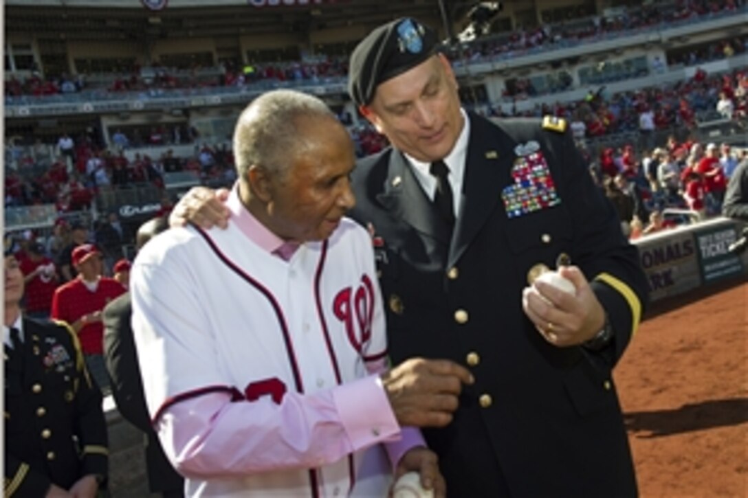 Army Chief of Staff Gen. Ray Odierno shows a baseball to Hall of Famer Frank Robinson, the first Nationals manager, before the game between the Washington Nationals and the St. Louis Cardinals at Nationals Park in Washington, D.C., Oct. 10, 2012. Robinson was honored with throwing the first pitch before the game.