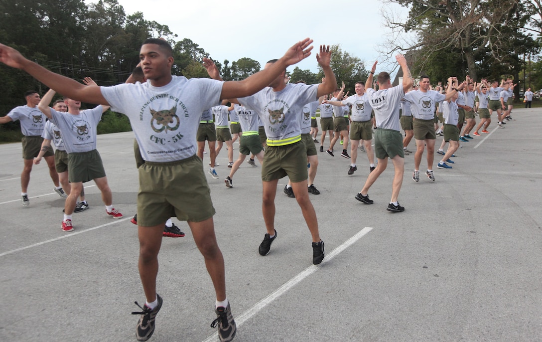 Marines conduct warm up exercises during the annual Headquarters and Support Battalion physical training session to support the Combined Federal Campaign at the Goettge Memorial Field House parking lot aboard Marine Corps Base Camp Lejeune Oct. 3. Those who donated 10 dollars for the event were able to compete against other racers and received shirts for bolstering the day's contributions.