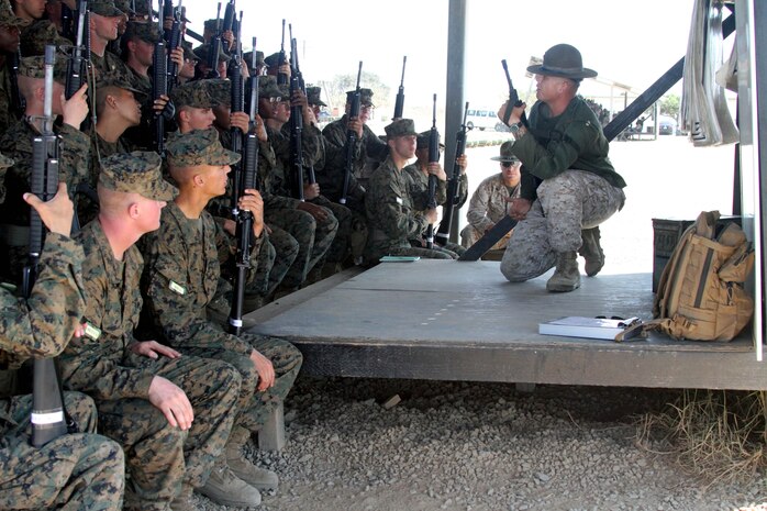 Sgt. Ryan Salinas, primary marksmanship instructor, Weapons Company, Weapons and Field Training Battalion, demonstrates the kneeling position to the recruits of Company F, 2nd Recruit Training Battalion, Oct. 2 at Edson Range aboard Marine Corps Base Camp Pendleton. Grass Week is dedicated to teaching the fundamentals of marksmanship and allows recruits to become comfortable with the weapon.