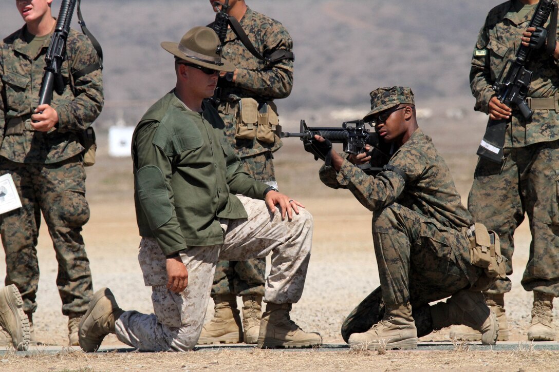 Sgt. Ryan Salinas, primary marksmanship instructor, Weapons Company, Weapons and Field Training Battalion, helps a recruit of Company F, 2nd Recruit Training Battalion, with his kneeling position while snapping in Oct. 2 at Edson Range aboard Marine Corps Base Camp Pendleton. Recruits snap in for hours, learning to be comfortable with each position before they head to the firing line the following week. 