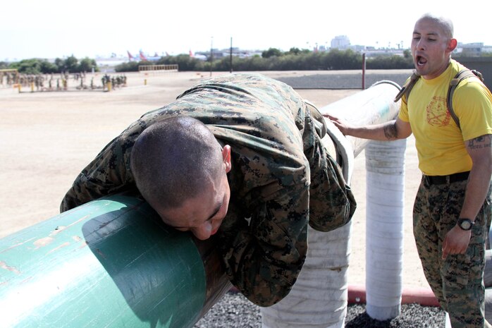 Sgt. Fortino Garica, drill instructor, Company E, 2nd Recruit Training Battalion, pushes a recruit through a portion of the "O-course" aboard Marine Corps Recruit Depot San Diego Oct 4. The "O-course" is a series of elevated bars, logs and walls that allows recruits to quickly maneuver through.