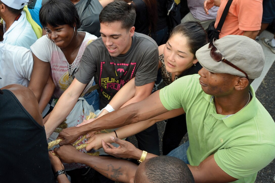 Seaman Greg C. Tramble, center, and Master Gunnery Sgt. Albert Wilson, right,  pitch in for the east team at the annual tug-of-war in downtown Naha Oct. 7. Tramble is a hospital corpsman with U.S. Naval Hospital Okinawa, and Wilson is the maintenance chief of 7th Communications Battalion, III Marine Expeditionary Force Headquarters Group, III MEF. 