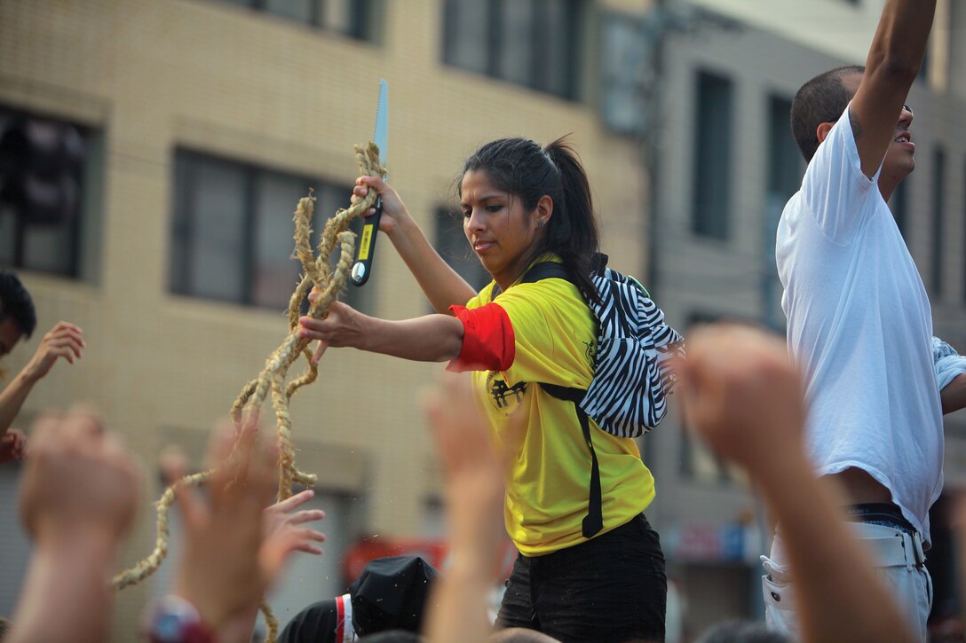 Cpl. Nanci Espinoza hands out pieces of rope following the conclusion of the tug-of-war in downtown Naha, Okinawa, Oct. 7. A piece of rope is believed to bring good luck to its owner. Espinoza is a supply administration and operation specialist with Marine Aircraft Group 36, 1st Marine Aircraft Wing, III Marine Expeditionary Force, and an event volunteer. 