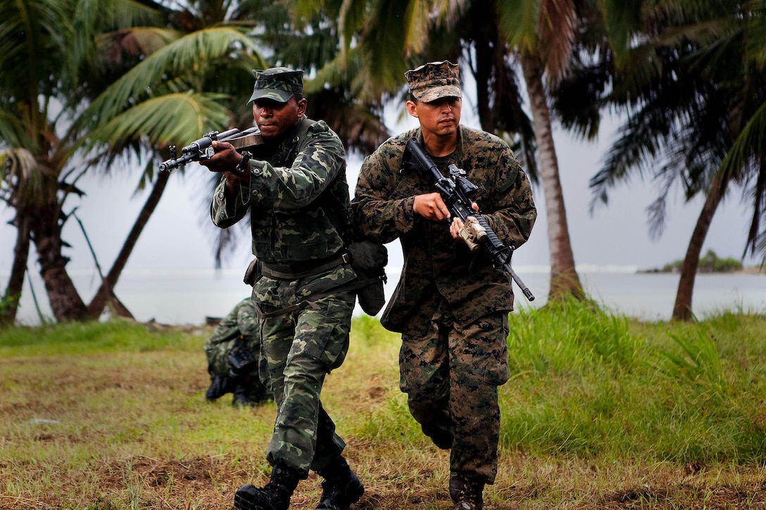 GAN, Republic of Maldives - Lance Cpl. Adam Haleem, a rifleman with Marine Deployment Unit 5 of the Maldivian National Defense Force, and Sgt. Sergio Zacarias, a squad leader with Company A, 1st Battalion, 4th Marine Regiment, run to their rally point during accountability training here Oct. 9 as part of Exercise Coconut Grove 2012. Coconut Grove is a bilateral training exercise conducted bi-annually between the U.S. Marine Corps and the MNDF.