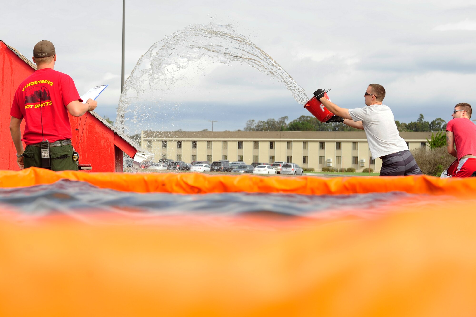 VANDENBERG AIR FORCE BASE, Calif. – Members of the 30th Comptroller Squadron throw buckets of water onto a roof during the bucket brigade portion of the Fire Muster competition here Friday, Oct. 12, 2012. The Fire Muster Competition marks the end of Fire Prevention Week and is a friendly competition of five-member teams racing to complete a series of feats simulating the rigorous training required of base firefighters. (U.S. Air Force photo/Senior Airman Lael Huss)