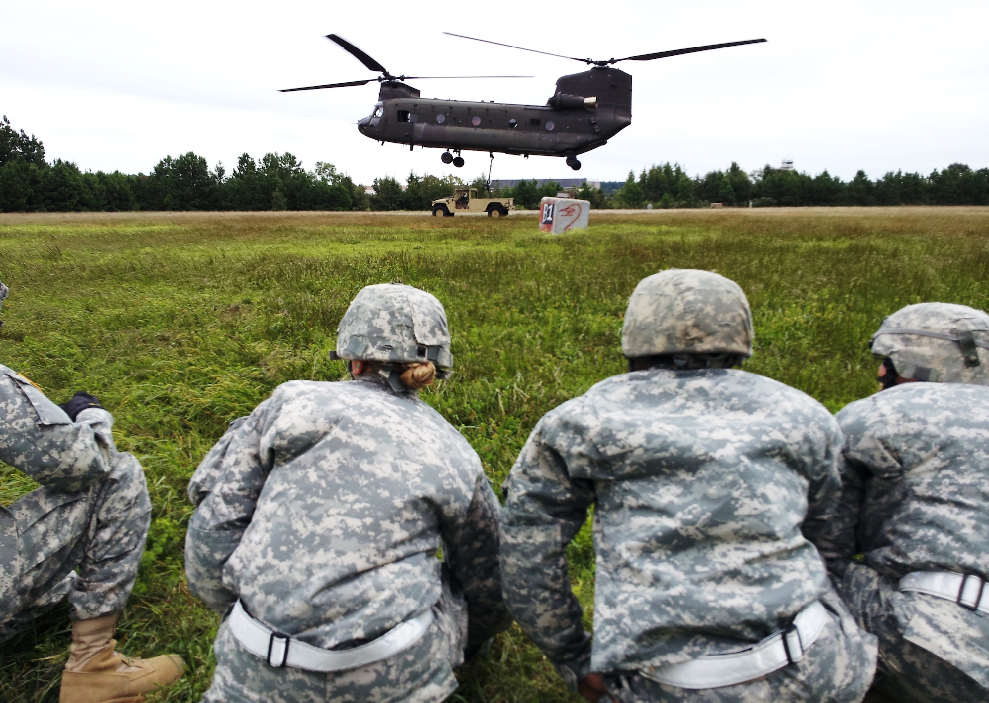 Soldiers assigned to the 53rd Movement Control Battalion, 7th Sustainment Brigade, watch a Chinook helicopter raise a Humvee during sling-load training at Felker Army Airfield on Fort Eustis, Va., recently. Army cargo specialists are trained to prepare, rig and load equipment for transport by rail, ground, sea and air. (U.S. Army photo by Sgt. 1st Class Brian Rhodes/Released)