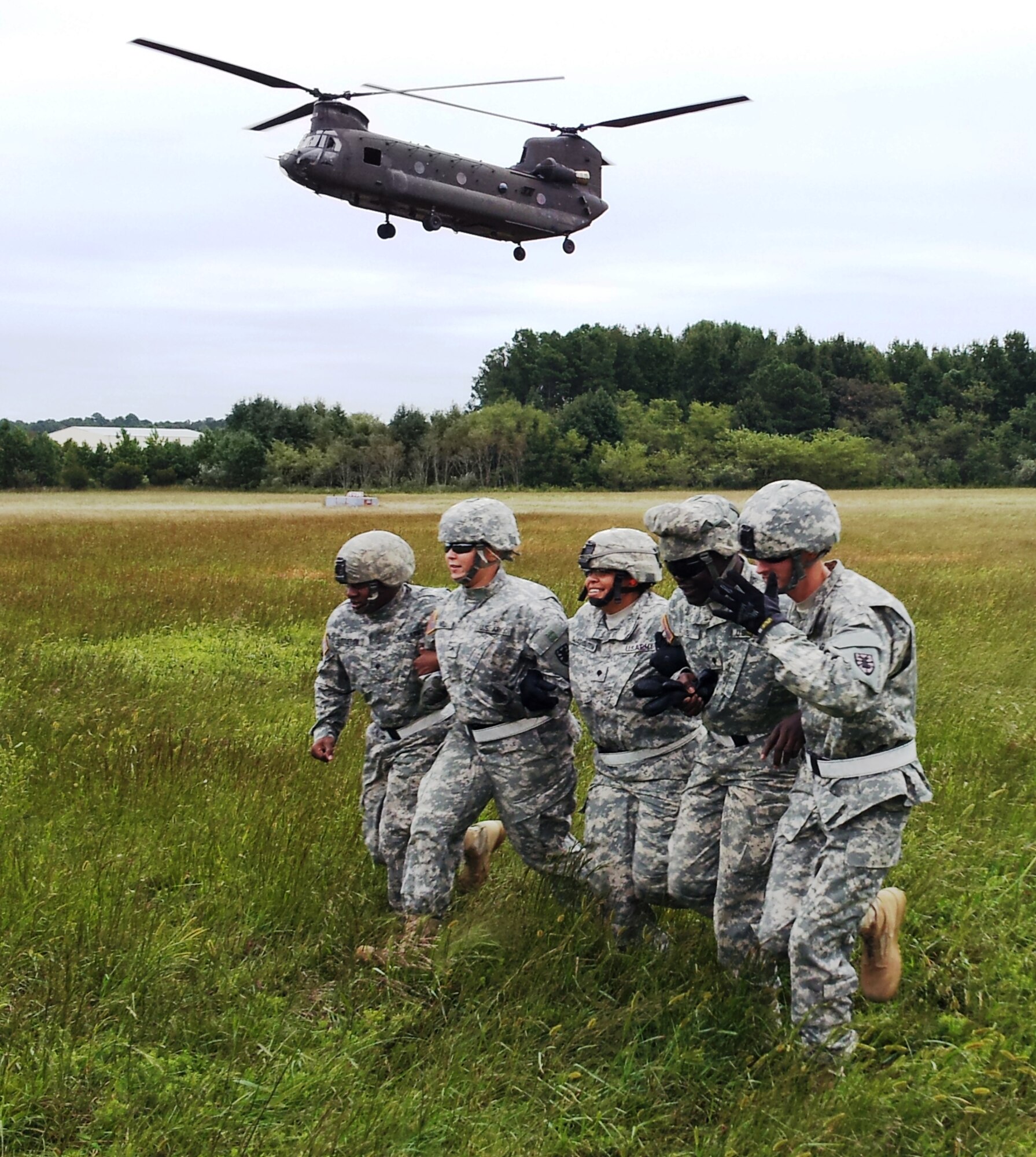 Soldiers assigned to the 53rd Movement Control Battalion, 7th Sustainment Brigade, run arm-in-arm away from the rotor wash of a Chinook helicopter during sling-load training at Felker Army Airfield on Fort Eustis, Va., recently. While some Soldiers are unfamiliar with sling load operations and procedures, the skill has a very real application to the current fight in Afghanistan. (U.S. Army photo by Sgt. 1st Class Brian Rhodes/Released)