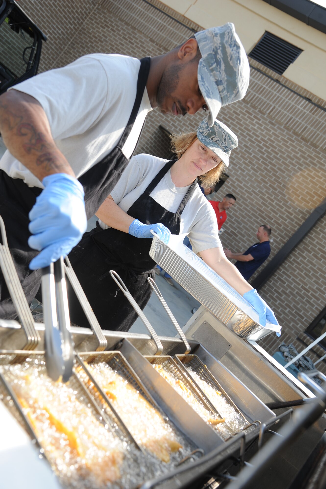 Staff Sgt. Brandon Leach, 81st Diagnostic and Therapeutics Squadron, and Master Sgt. Tammy Pfeifer, 2nd Air Force, fry cat fish during retiree appreciation day Oct. 12, 2012, at the Roberts Consolidated Aircraft Maintenance Facility, Keesler Air Force Base, Miss.  The event included information booths, guest speakers and lunch.  (U.S. Air Force photo by Kemberly Groue)