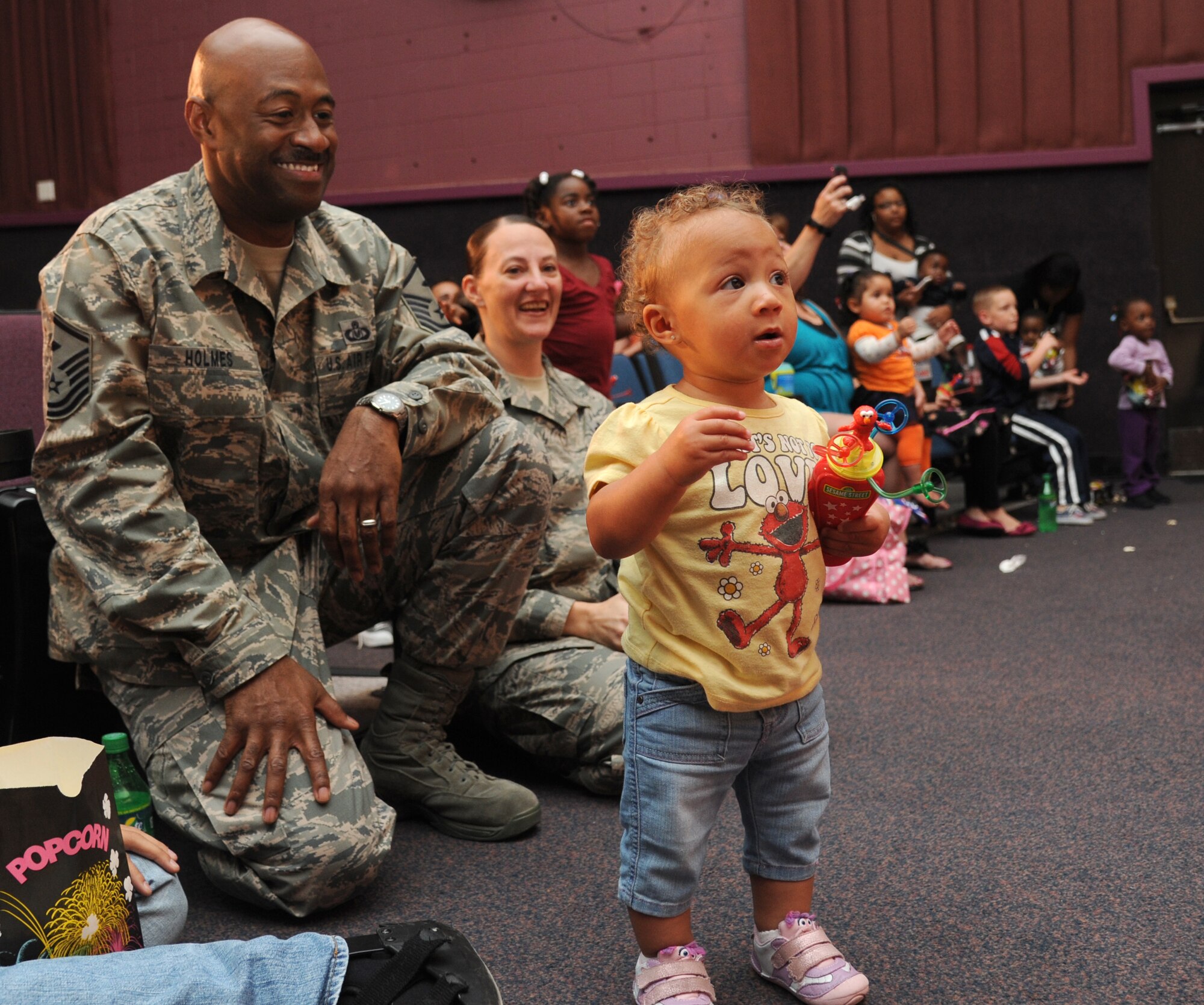 Master Sgts. Kevin Holmes, 81st Medical Operations Squadron, and Laurie Holmes, 334th Training Squadron, watch their one-year-old daughter, Mariah, dance to the production of the Sesame Street characters during a Sesame Street/USO Experience for Military Families Oct. 9, 2012 at the Welch Theater, Keesler Air Force Base, Miss.  The 45-minute family-oriented event hosted by the 81st Force Support Squadron includes a character named Katie who is a military child.  With the help of her Sesame pals, Katie learns to deal with her fears and excitement about relocating.  The show emphasizes the importance of adjusting to change and the power of friendship.  (U.S. Air Force photo by Kemberly Groue)