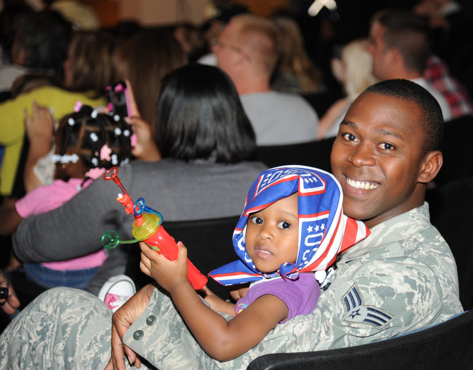 Senior Airman Felton Martin, 81st Security Forces Squadron, and his three-year-old daughter, Falyn, watch as Sesame Street characters  arrive on stage during the Sesame Street/USO Experience for Military Families show Oct. 9, 2012 at the Welch Theater, Keesler Air Force Base, Miss.  The 45-minute family-oriented event hosted by the 81st Force Support Squadron includes a character named Katie who is a military child.  With the help of her Sesame pals, Katie learns to deal with her fears and excitement about relocating.  The show emphasizes the importance of adjusting to change and the power of friendship.  (U.S. Air Force photo by Kemberly Groue)