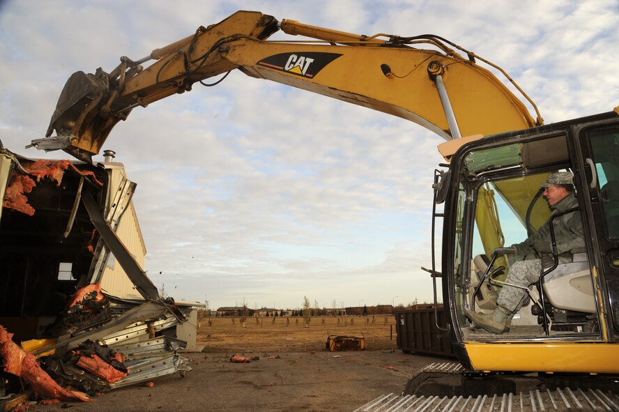 Col. Tim Bush, 319th Air Base Wing commander, assists in tearing down building 432 on Oct. 12, 2012, on Grand Forks Air Force Base, N.D. The building was being torn down in keeping up with Air Force initiatives to clear all outdated and under-utilized buildings. (U.S. Air Force photo/Senior Airman Amber Bennett)