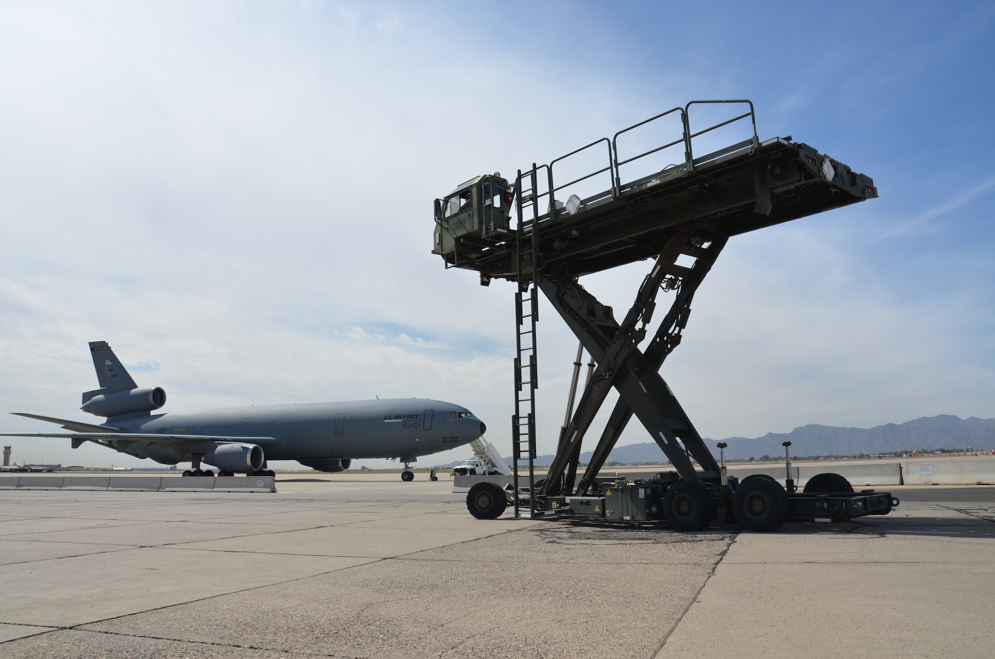 An extended 25,000-pound-capacity Halvorsen sits on the Luke Air Force Base aircraft parking ramp in front of a KC-135 Stratotanker. The Halvorsen is an air transportable, self propelled mobile air cargo transporter and loader that supports all military transport and civil reserve air fleet aircraft. The loader is capable of interfacing with the deck and lower lobe cargo doors of commercial and military cargo aircraft.  (Courtesy photo)