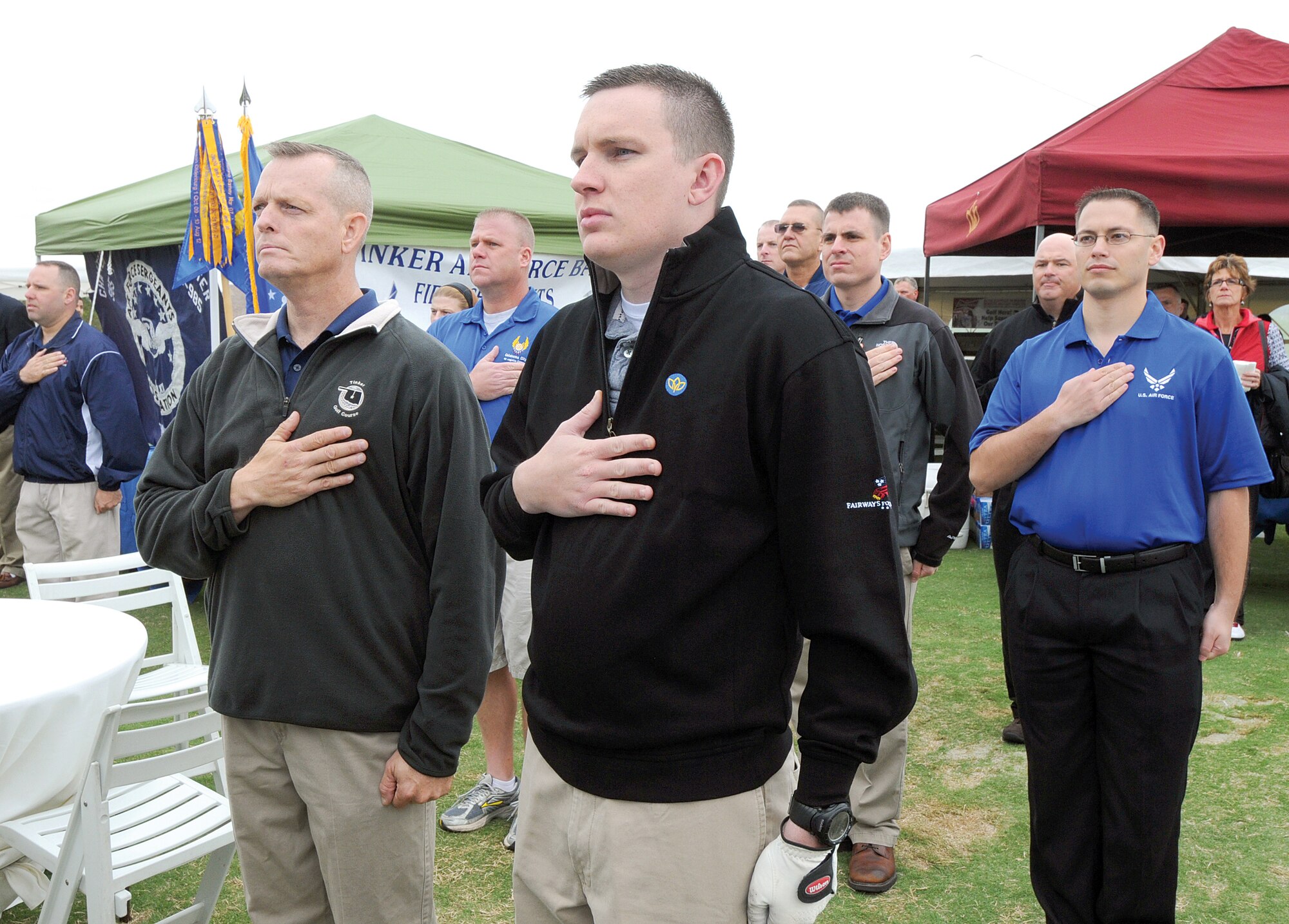 Volunteers from Tinker organizations staffed an information booth at the Fairways for Freedom golf tournament in Oklahoma City Oct. 5, showing their support in the community for those wounded while serving. Standing with Tinker supporters, Senior Airman Michael Helsdingen, a Wounded Warrior from the 72nd Security Forces Squadron Armory, foreground center, honors the national anthem during opening ceremonies before joining the other golfers. Beside him, left, is Master Sgt. Michael Bartels, 552nd Air Control Networking Squadron first sergeant. First Lt. Joseph Owens, president of the Tinker Company Grade Officer’s Council is far right.  (Air Force photo by Margo Wright)