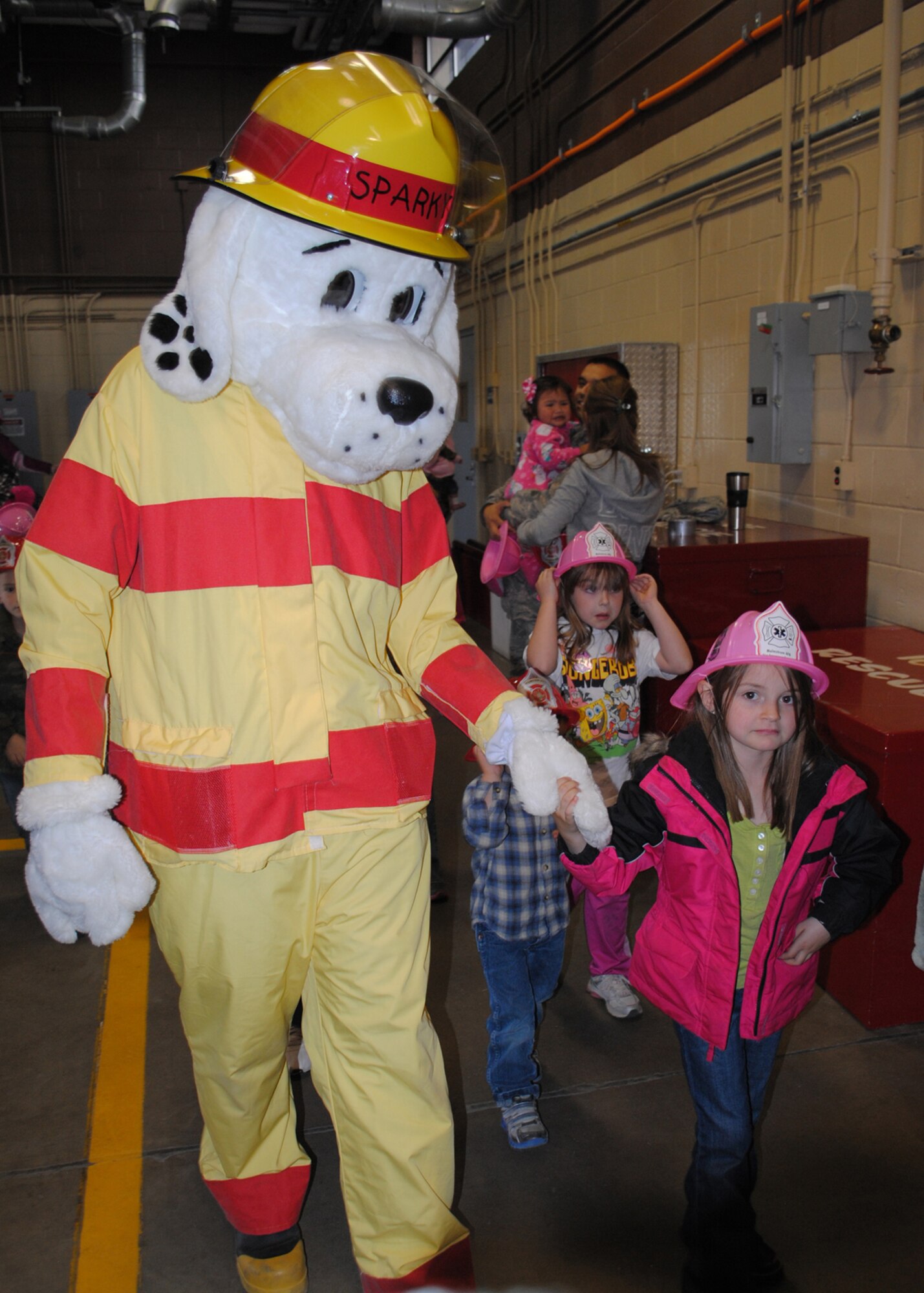Sparky the Fire Dog walks a Loy Elementary School kindergartener to the next part of their tour.  During their tour, several fire fighters taught the children various ways to prevent fires and what to do if a fire did occur in their house.  (U.S. Air Force photo/Airman 1st Class Cortney Paxton)