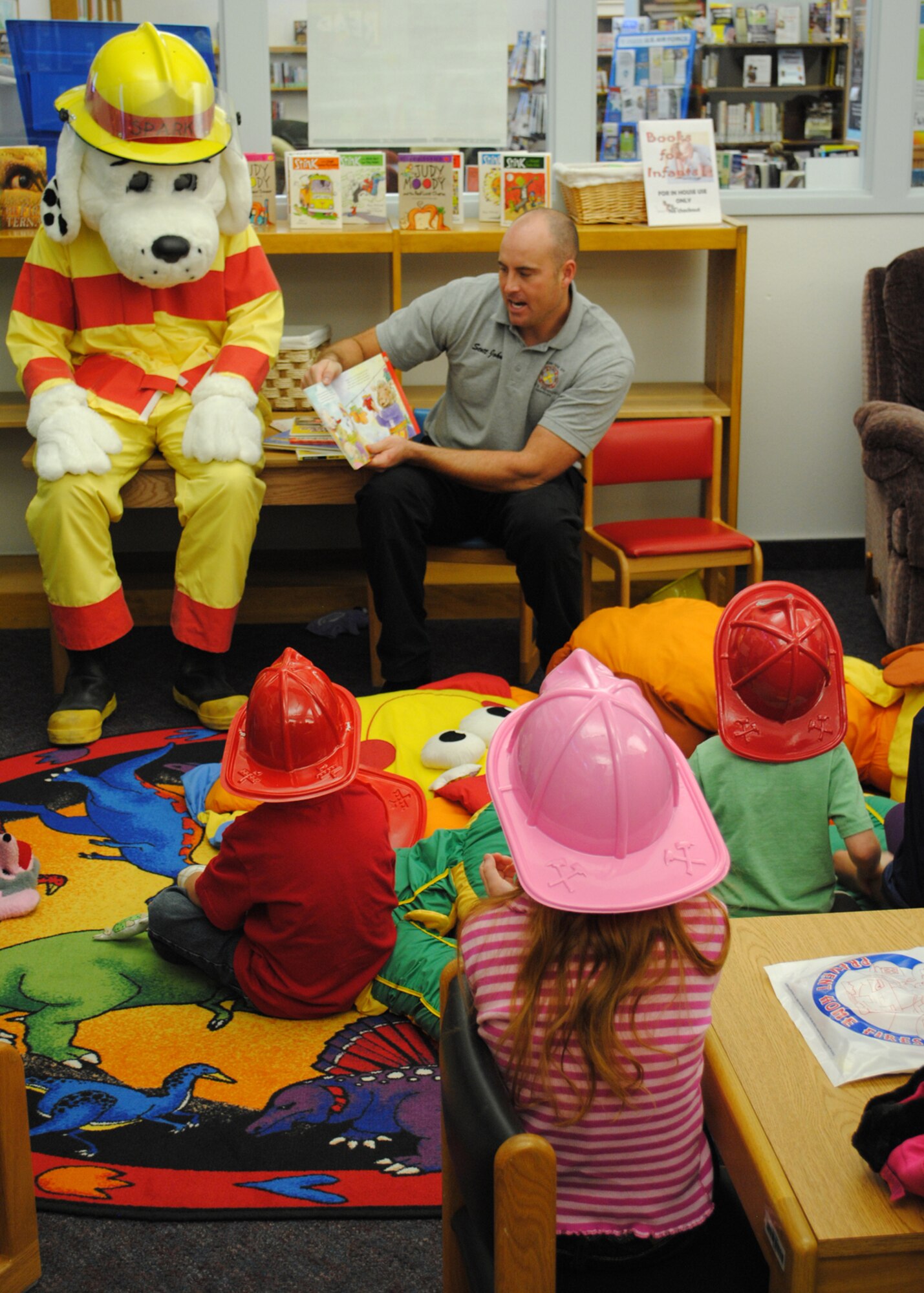 Scott Johns, 341st Civil Engineer Squadron fire fighter, reads a book to children at the Library on Oct. 9 in celebration of Fire Prevention Week.  Various displays, briefings and events took place during the week, which was celebrated from Oct. 7 to Oct. 13.  (U.S. Air Force photo/Airman 1st Class Cortney Paxton)
