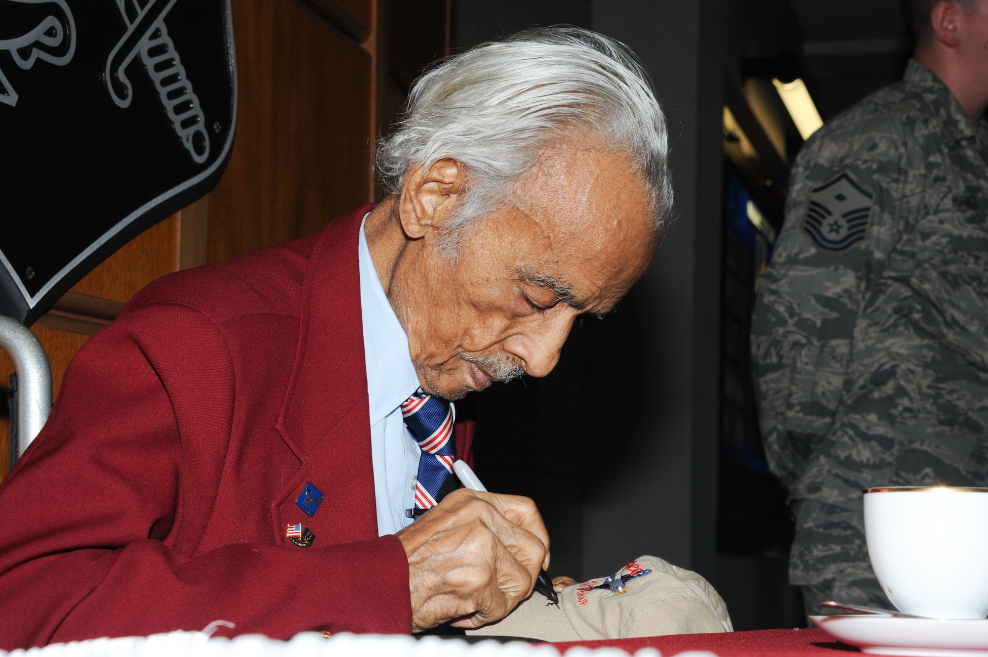 Retired Lt. Col. Herbert "Gene" Carter, one of the original Tuskegee Airmen, who flew in the famous Red Tail squadron during WWII, signs personal items and memorabilia after the ceremony. (Air Force photo by Bud Hancock)