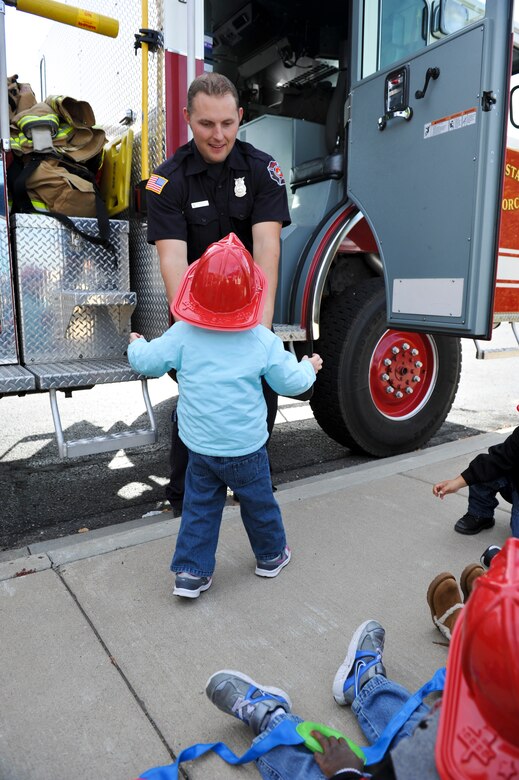 BUCKLEY AIR FORCE BASE, Colo. – Brandon Elson, Buckley Fire Department, lifts a child into a fire truck Oct. 11, 2012, at a Buckley Child Development Center during Fire Prevention Week. Children received plastic fire helmets, coloring books, stickers and pamphlets to make learning about fire prevention fun. Firemen and Sparky the Fire Dog were answered children’s questions and to show the ins and outs of a fire truck. (U.S. Air Force photo by Senior Airman Christopher Gross)