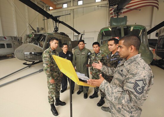Master Sgt. Guadalupe Arredondo, instructor-supervisor, 318th Training Squadron, right, discusses helicopter towing procedures with, from left to right, students E-1 Powell Murillo, Colombia, O-2 Julio Hortiales, Mexico, E-6 Fernando Toscano, Argentina, E-1 Yamid Camacho, Colombia, and guest instructor PNGI E-8 Mario Ordoñez, Honduras, prior to moving an Army Huey UH-1H helicopter outside the Inter-American Air Forces Academy’s Airfield Training Complex High Bay Oct. 1. The UH-1H will be used to train students from Latin American partner nations. (U.S. Air Force photo/Robbin Cresswell)