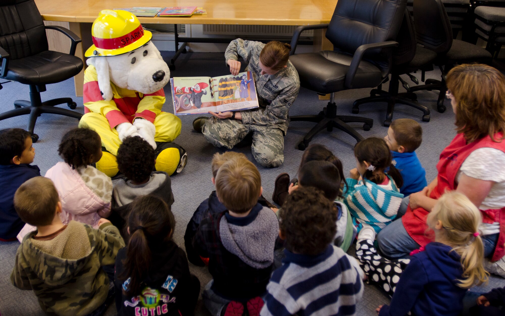 ROYAL AIR FORCE LAKENHEATH, England – Sparky the Fire Dog and Airman 1st Class Ashley Eisenbarth, 48th Civil Engineer Squadron firefighter, read a book to preschoolers from the Child Development Center West at the base library during Fire Prevention Week Oct. 11, 2012. Throughout the week, the 48th CES firefighters coordinated a series of events to raise awareness and Liberty Wing members about fire prevention. (U.S. Air Force photo by Staff Sgt. Stephen Linch) 