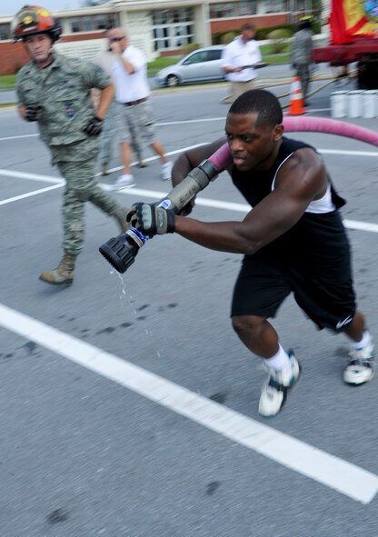 U.S. Air Force Senior Airman Jerod Christian, 18th Civil Engineer Squadron operations management journeyman, runs to get in position to knock over a cone with water from a fire hose during the second annual Fire Muster team building event on Kadena Air Base, Japan, Oct. 12, 2012. This year's Fire Muster was a relay race, where members of different squadrons were challenged through various carries and firefighting procedures. (U.S. Air Force photo/Airman 1st Class Justin Veazie)