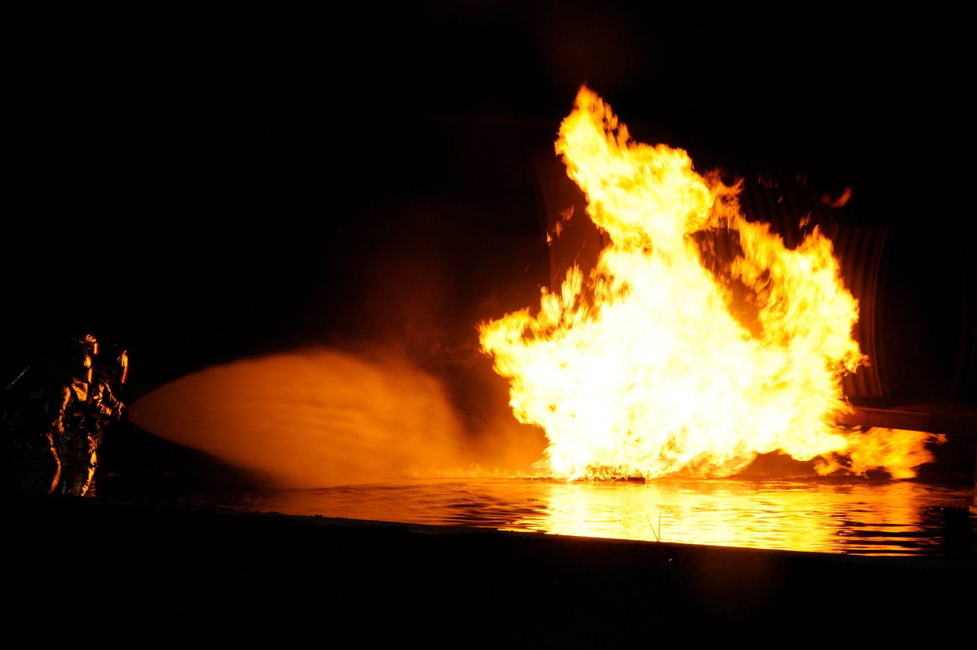Firefighters from the 35th Civil Engineer Squadron prepare to enter a burning mock training aircraft at a nighttime firefighting demonstration during Fire Prevention Week at Misawa Air Base, Japan, Oct. 10, 2012. This week, the 35 CES has been educating base community members on fire prevention in order to promote a fire-safe lifestyle.  (U.S. Air Force photo by Tech. Sgt. Marie Brown)