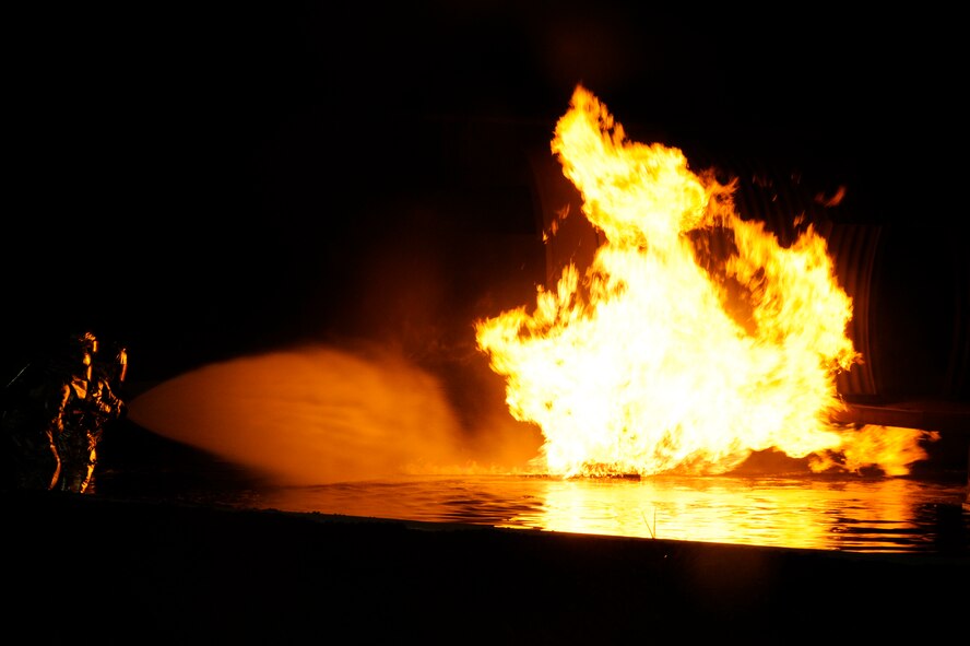 Firefighters from the 35th Civil Engineer Squadron prepare to enter a burning mock training aircraft at a nighttime firefighting demonstration during Fire Prevention Week at Misawa Air Base, Japan, Oct. 10, 2012. This week, the 35 CES has been educating base community members on fire prevention in order to promote a fire-safe lifestyle.  (U.S. Air Force photo by Tech. Sgt. Marie Brown)