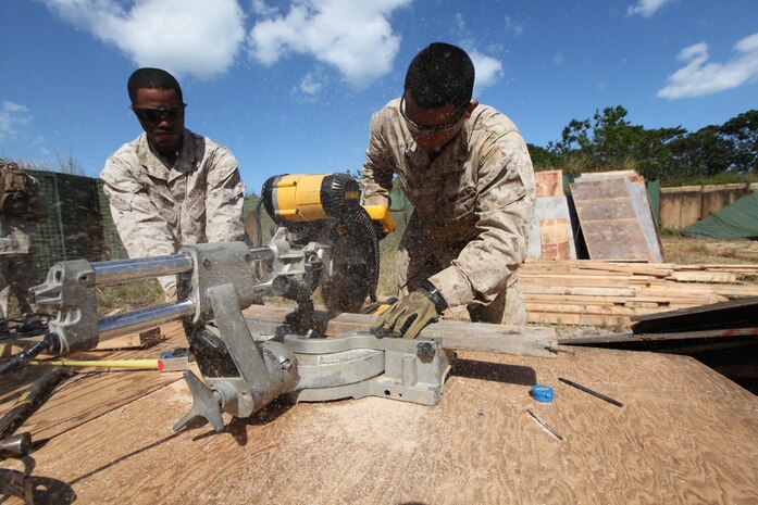 Lance Cpl. Montae R. Johnson (left) and Lance Cpl. Michael H. Alfaro (right) cut a piece of wood using a miter saw at the Central Training Area, Camp Hansen Oct. 3. Marines repaired huts in the CTA which can be used to shelter Marines, store ammunition and equipment, or function as office spaces during training evolutions. Johnson and Alfaro are combat engineers with Company A, 9th Engineer Support Battalion, 3rd Marine Logistics Group, III Marine Expeditionary Force. 