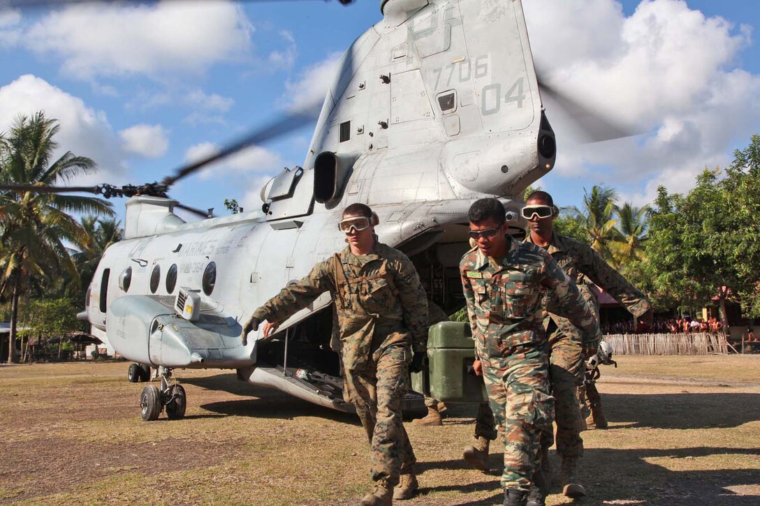 Marines from Combat Logistics Battalion 15, 15th Marine Expeditionary Unit, and a soldier from the Timor-Leste Defense Force (F-FDTL) carry engineering supplies off a CH-46E Sea Knight during a humanitarian mission at a remote village in Timor-Leste. The 15th MEU is participating in Exercise Crocodilo 2012, an event between the MEU and F-FDTL that focuses on bilateral training and community relations.