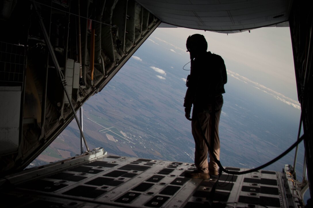 Lance Cpl. Benjamin Lockyer, a loadmaster with Marine Aerial Refueler Transport Squadron 252, peers out the back of a KC-130J Hercules at the Indiana landscape below Sept. 30.  VMGR-252 transported 21 Marines from 2nd Marine Special Operations Battalion, Marine Corps Forces Special Operations Command, to Indiana to conduct urban environment training for two weeks at Camp Atterbury Joint Maneuver Training Center .