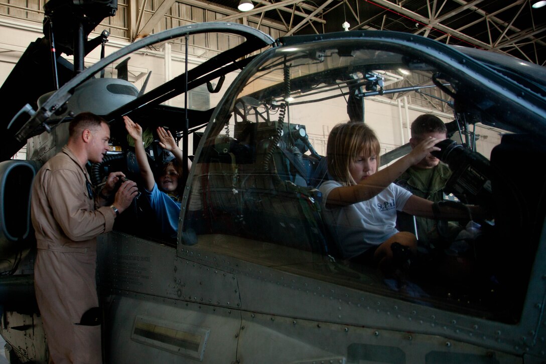 Two young girls take the controls of an AH-1W Cobra during a visit to Marine Corps Air Station Cherry Point Sept. 26. Twenty-eight students from St. Paul Catholic School in nearby New Bern, N.C., took a field trip to the air station to visit the Hercules squadron and Marine Light Attack Helicopter Squadron 467. Maj. Scott Weinpel, left, an AH-1W Cobra pilot with HMLA-467, showed the students around the squadron’s attack helicopters and said, “Anytime we can give back to the community, that’s what this is about.”