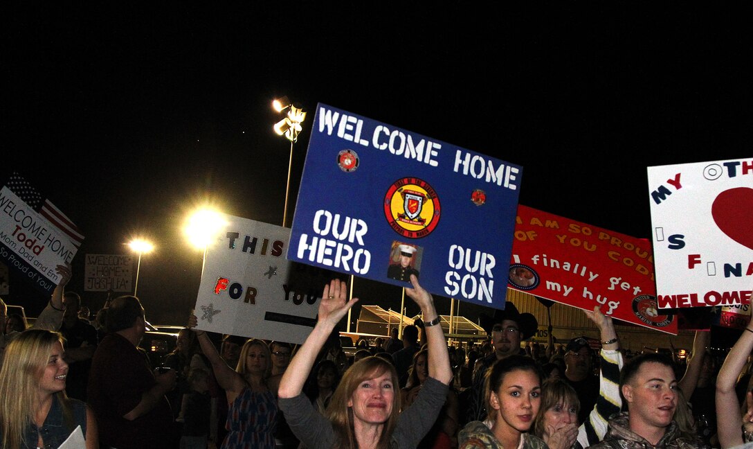 Families and friends cheer and hold signs as the returning members of 1st Battalion, 7th Marine Regiment, march onto Del Valle Field, Sunday. Marines from Companies A, B, D, and H&S returned home from their 7-month long deployment to Sangin, Afghanistan.