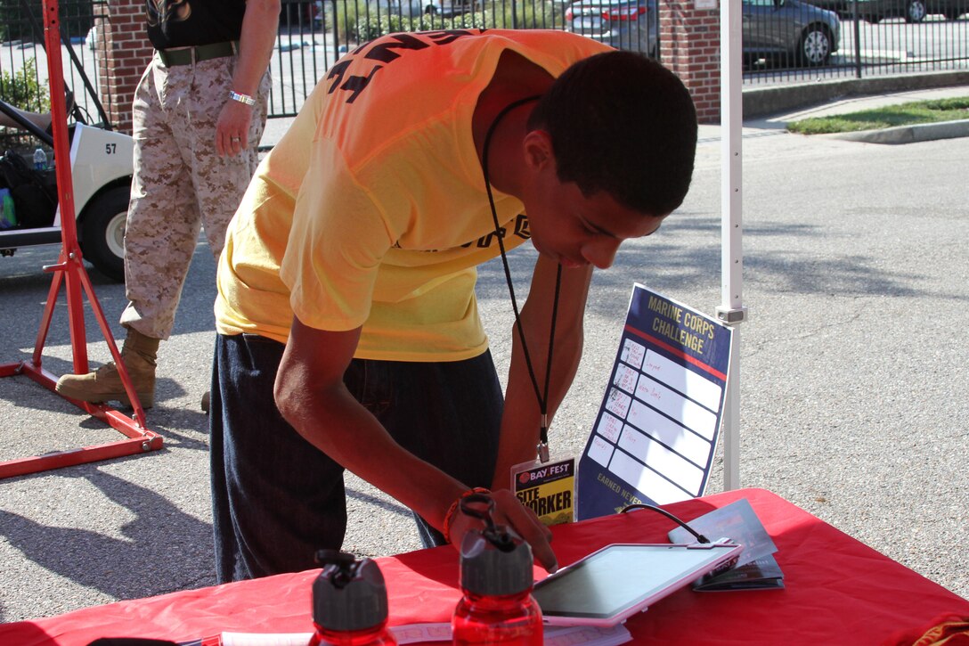 A worker with the Bayfest Music Festival 2012 takes a beak from his duties to attempt Marine Corps style pull-ups at the Marine Corps Booth October 6, 2012.
