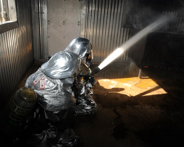 Members of 8th Fighter Wing leadership put out a simulated fire during fire safety week at Kunsan Air Base, Republic of Korea, Oct. 12, 2012. The officers received training and experienced rescuing a person from a burning building while trying to extinguish the flames. (U.S. Air Force photo/Senior Airman Marcus Morris)