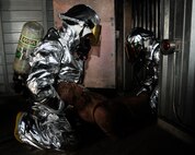 Members of 8th Fighter Wing leadership drag out a 180-pound rescue dummy from a building during fire safety week at Kunsan Air Base, Republic of Korea, Oct. 12, 2012. Responders had to stay low to avoid the heat and smoke from the simulated fire. (U.S. Air Force photo/Senior Airman Marcus Morris)