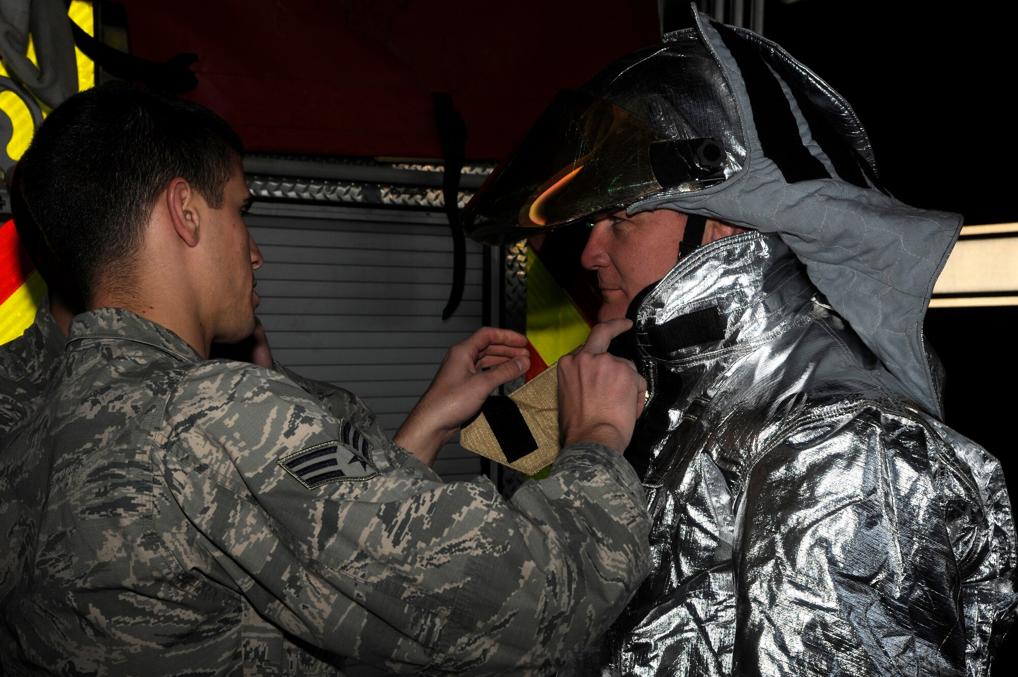 Senior Airman Aaron Strayhorn, left, 8th Civil Engineer Squadron firefighter, fits Col. John Pearse, 8th Fighter Wing commander with a fire proximity suit to show leadership what it is like to be in the firefighters’ shoes during fire safety prevention week at Kunsan Air Base, Republic of Korea, Oct. 12, 2012. Firefighters must do buddy checks to ensure no body parts are exposed to fire. (U.S. Air Force photo/Senior Airman Marcus Morris)