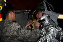 Senior Airman Aaron Strayhorn, left, 8th Civil Engineer Squadron firefighter, fits Col. John Pearse, 8th Fighter Wing commander with a fire proximity suit to show leadership what it is like to be in the firefighters’ shoes during fire safety prevention week at Kunsan Air Base, Republic of Korea, Oct. 12, 2012. Firefighters must do buddy checks to ensure no body parts are exposed to fire. (U.S. Air Force photo/Senior Airman Marcus Morris)