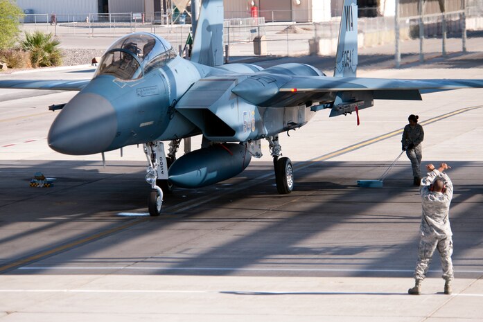 Senior Airman Anthony Ewing, dedicated crew chief, 757th Aircraft Maintenance Squadron prepares to marshal an F-15D Eagle Oct. 14, 2012, at Nellis Air Force Base, Nev. Retired United States Air Force Brig. Gen. Charles E. "Chuck" Yeager and Capt. David Vincent, 65th Aggressor Squadron pilot will fly the speed of sound marking the 65th anniversary of breaking of the sound. (U.S. Air Force photo by Lawrence Crespo)