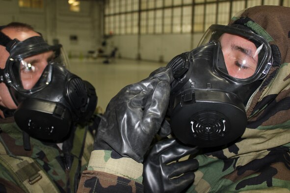 Staff Sgt. Jason Bucholtz, 127th Logistics Readiness Squadron, left, helps adjust the gas mask and protective suit worn by Airman 1st Class Robert Kolman, 127th Maintenance Squadron, during a training session on how to properly wear and operate in the gear, Oct. 13, 2012. Airmen at Selfridge Air National Guard Base participated in the training as part of an overall “readiness rodeo” in October. (Air National Guard photo by TSgt. Dan Heaton) 